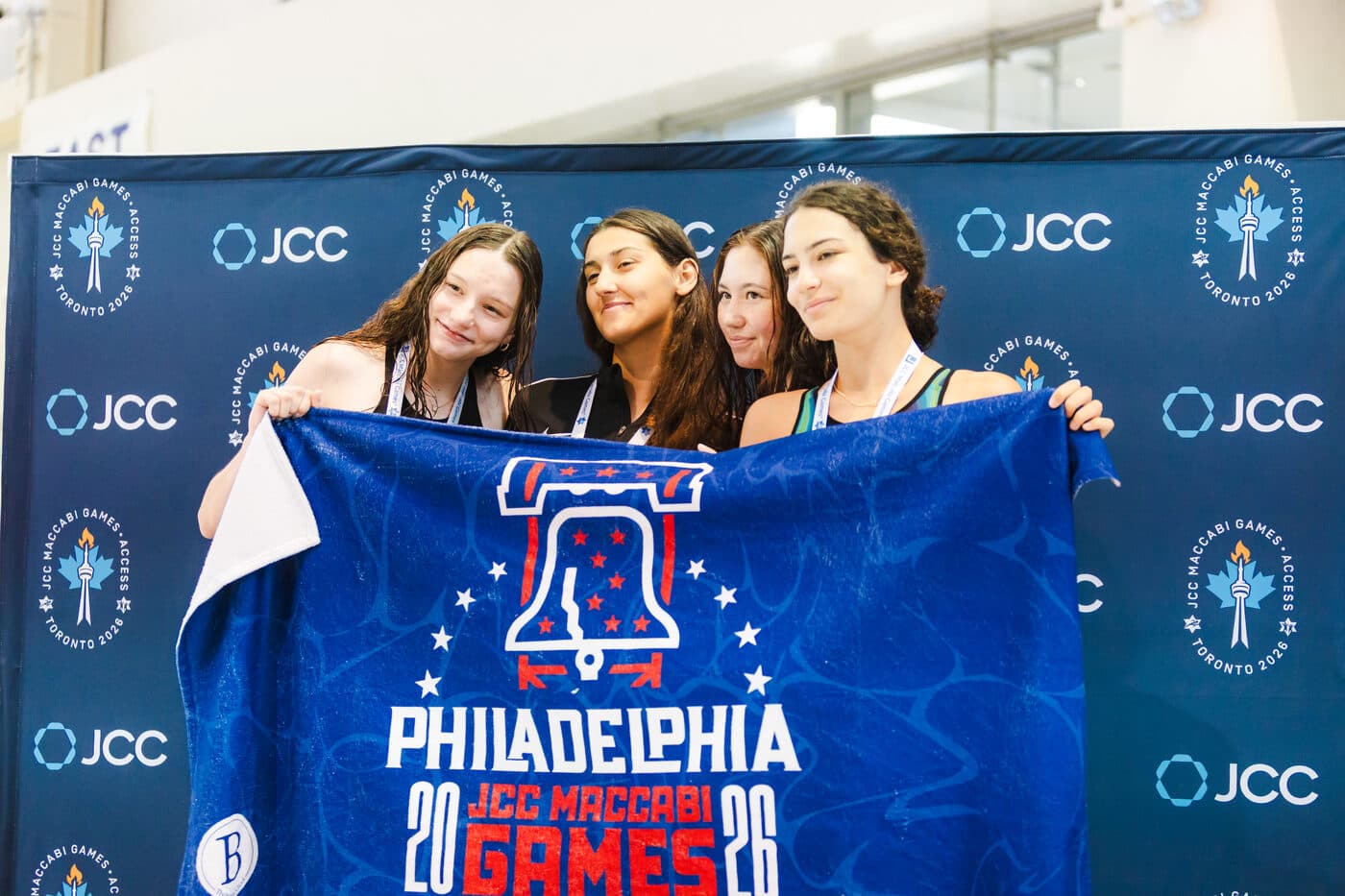 Teammates holding up a Philadelphia JCC Maccabi Games banner